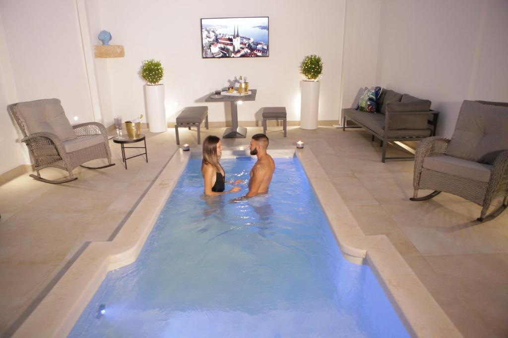 a man and a woman sitting in a swimming pool at Pasitea Luxury Suite in Squinzano