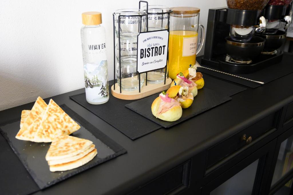 une table avec deux plaques noires de nourriture et un verre de jus d'orange dans l'établissement BB LETTERARIO, à Ravenne