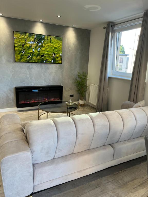 duża biała kanapa w salonie z kominkiem w obiekcie Strada Apartment w Edynburgu