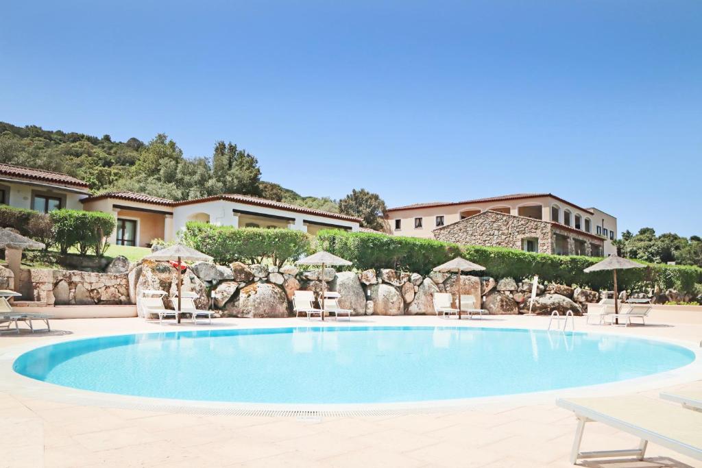 una grande piscina con sedie e ombrelloni di Hotel Valkarana Country Relais a Sant'Antonio di Gallura