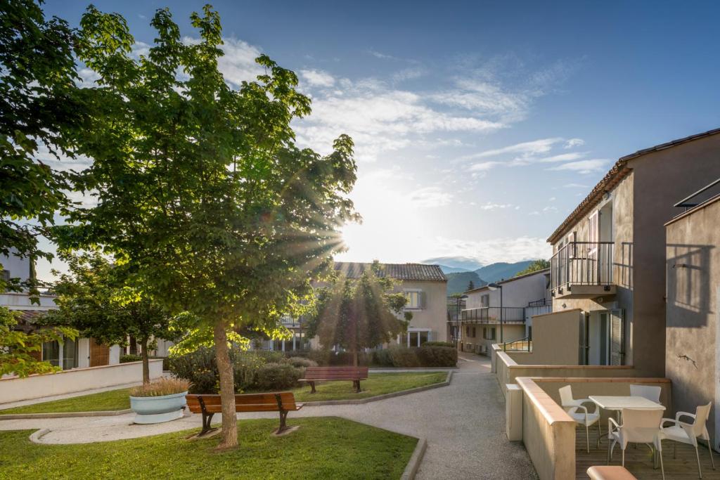 un parque con bancos y un árbol en un patio en Garden & City Mont-Ventoux Malaucène en Malaucène