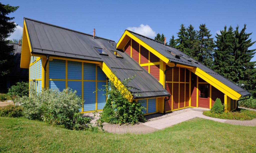 żółto-pomarańczowy dom z czarnym dachem w obiekcie Ferienhaus Nr 3 Sporthotel Oberhof w mieście Oberhof