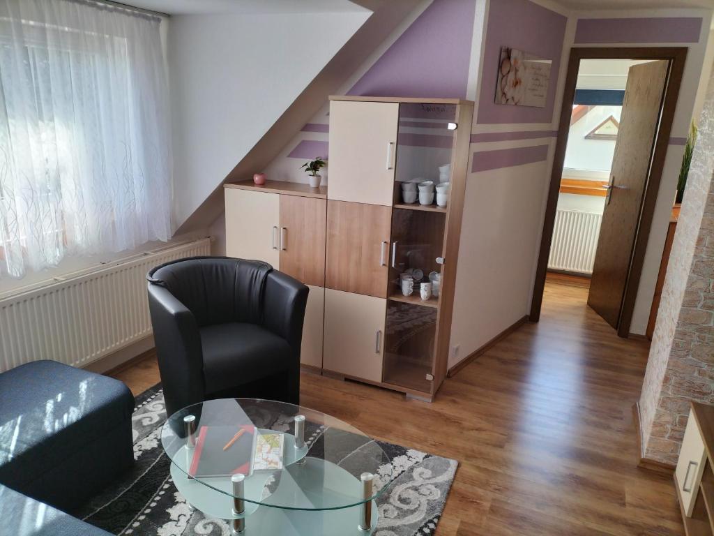 a living room with a glass table and a chair at FeWo Zur Alten Drechslerei in Freital