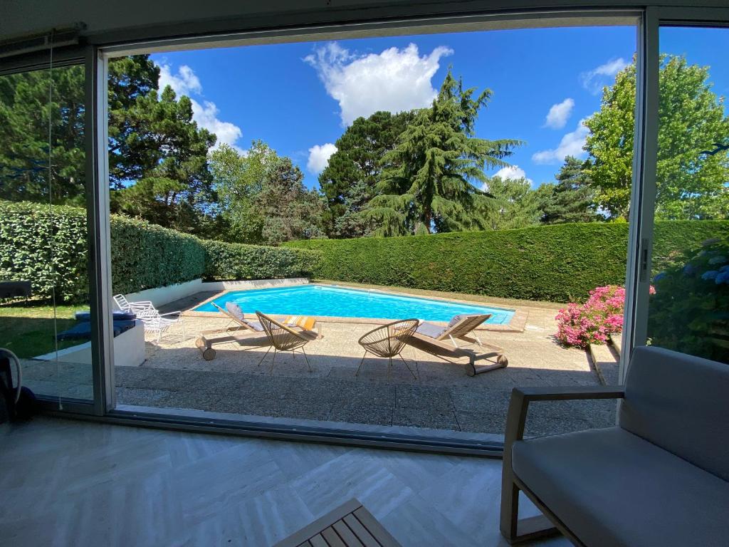 a view of a swimming pool through a sliding glass door at Villa 96 Golf de la Baule avec piscine et spa in Saint-André-des-Eaux