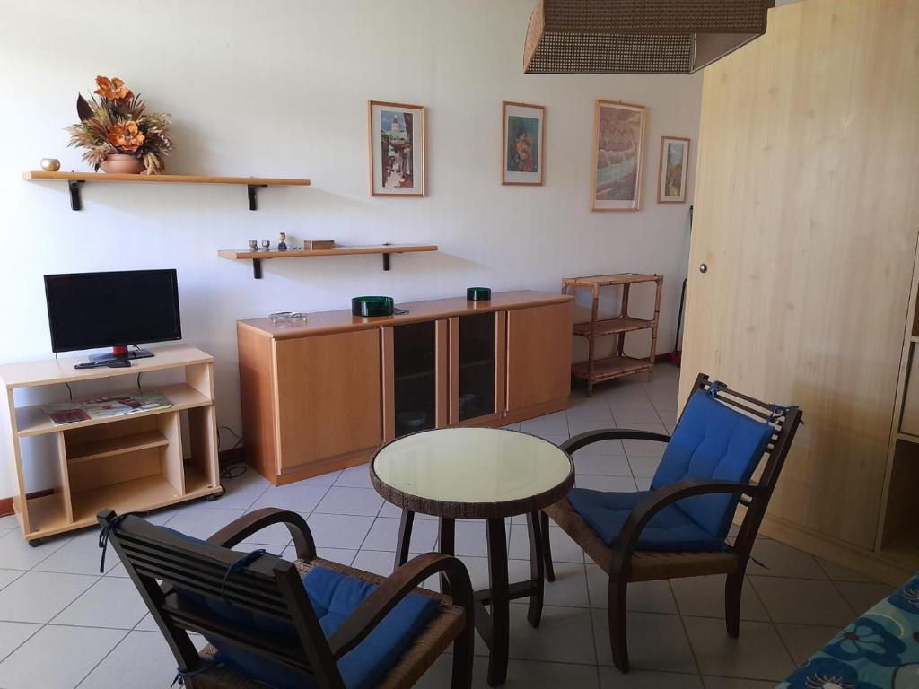 uma sala de estar com uma mesa e cadeiras e uma televisão em Marina di Bibbona - Lotto B em Marina di Bibbona