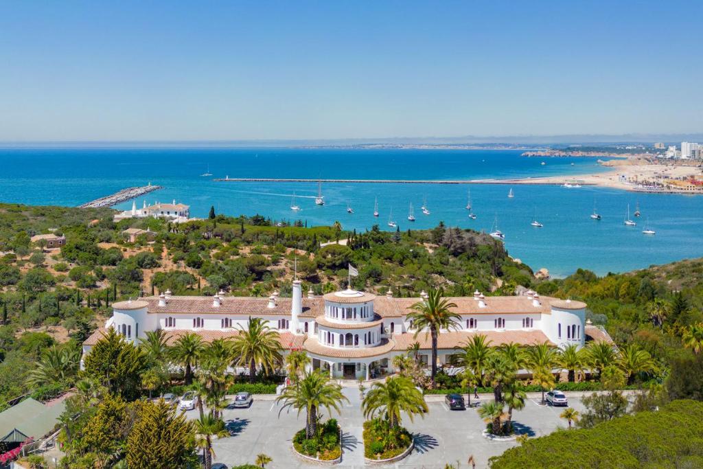 una vista aérea de una gran casa con palmeras y el océano en Hotel Casabela en Ferragudo