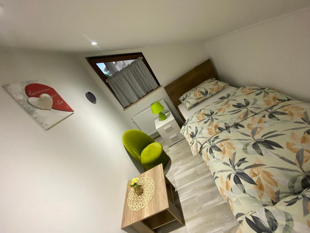 una piccola camera con letto e sedia verde di Apartman FILIP a Udbina