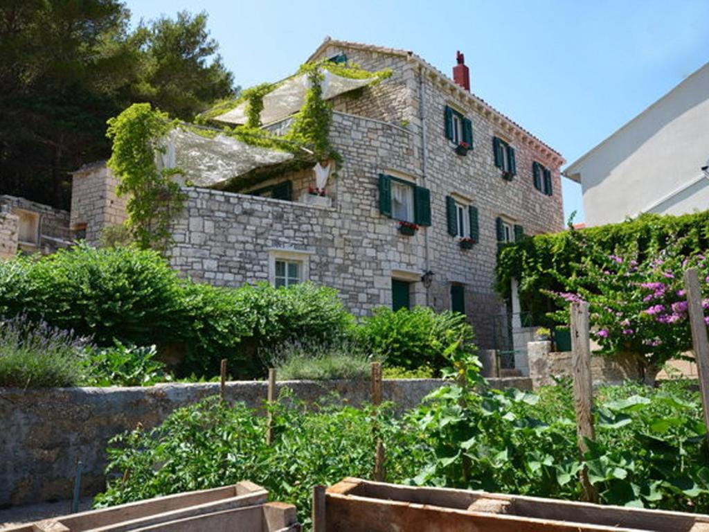 an old stone building with ivy growing on it in a garden at Villa Povlja in Povlja