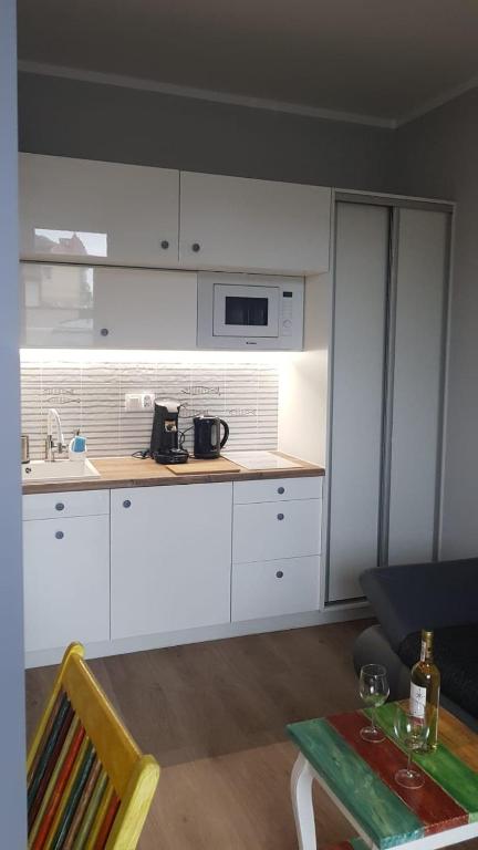 kuchnia z białymi szafkami i stołem w pokoju w obiekcie Uroczy Apartament Happy 01 z widokowym tarasen na dachu - tuż przy plaży !!! w mieście Niechorze