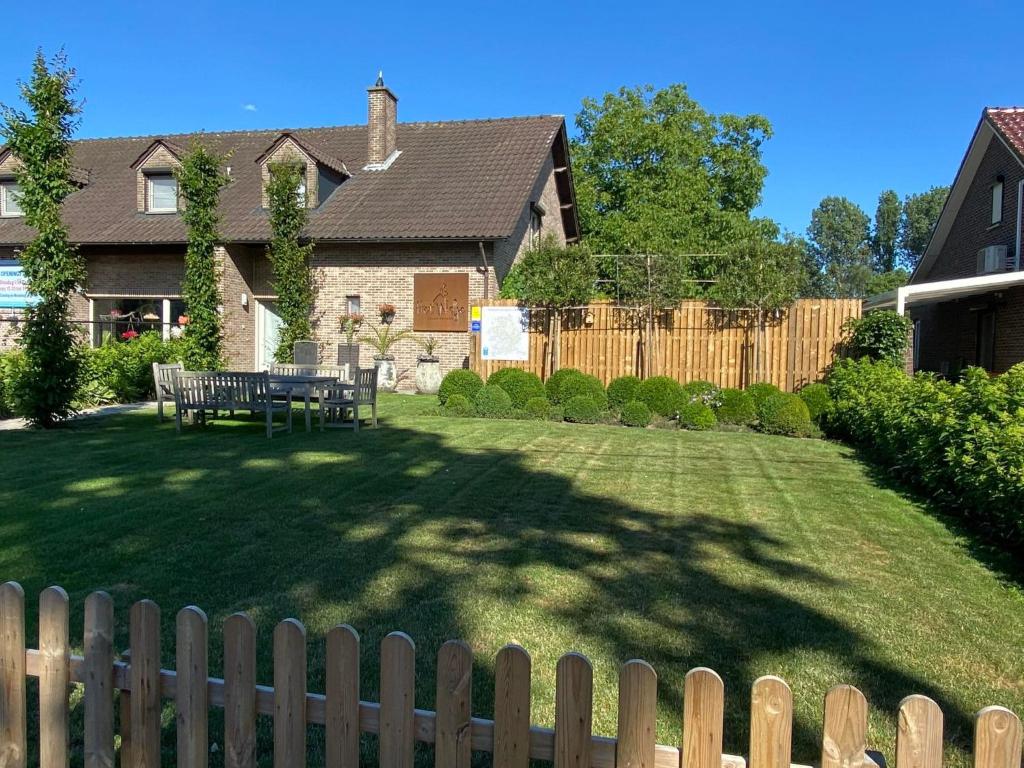 een achtertuin met een houten hek en een tafel in de tuin bij Vakantiewoning Het Wielje Maasland in Kinrooi