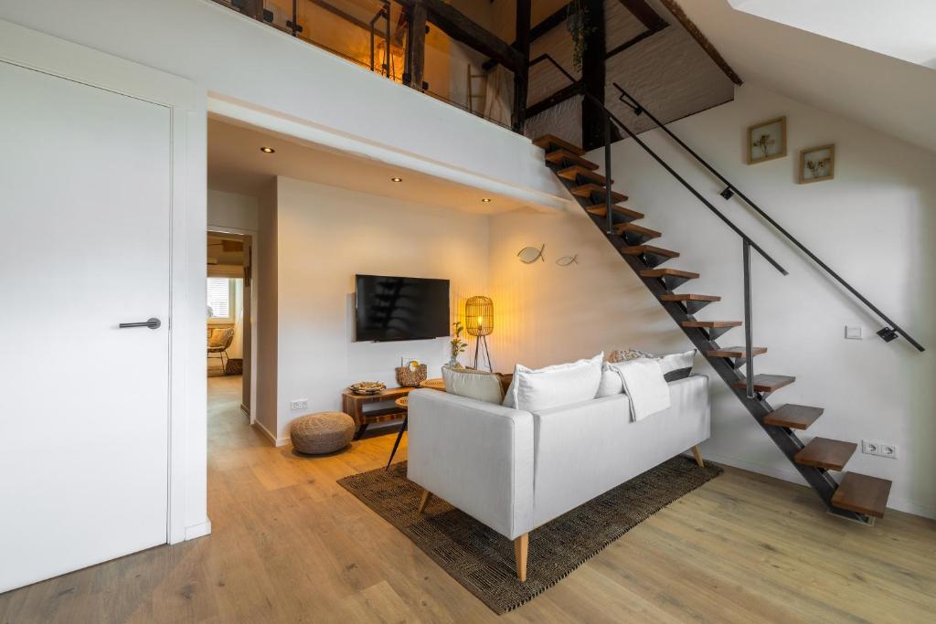 salon z białą kanapą i spiralnymi schodami w obiekcie Madrid Suites w mieście Maastricht