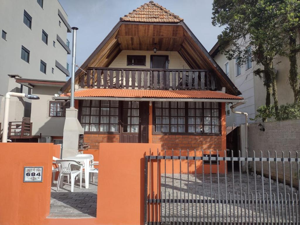 Apartamento estilo chalé - Enxaimel في بومبينهاس: منزل أمامه سور برتقالي