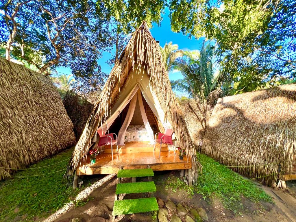 a cabin with chairs and a thatch roof at Z'Alpes Camping e Restaurante in Tianguá