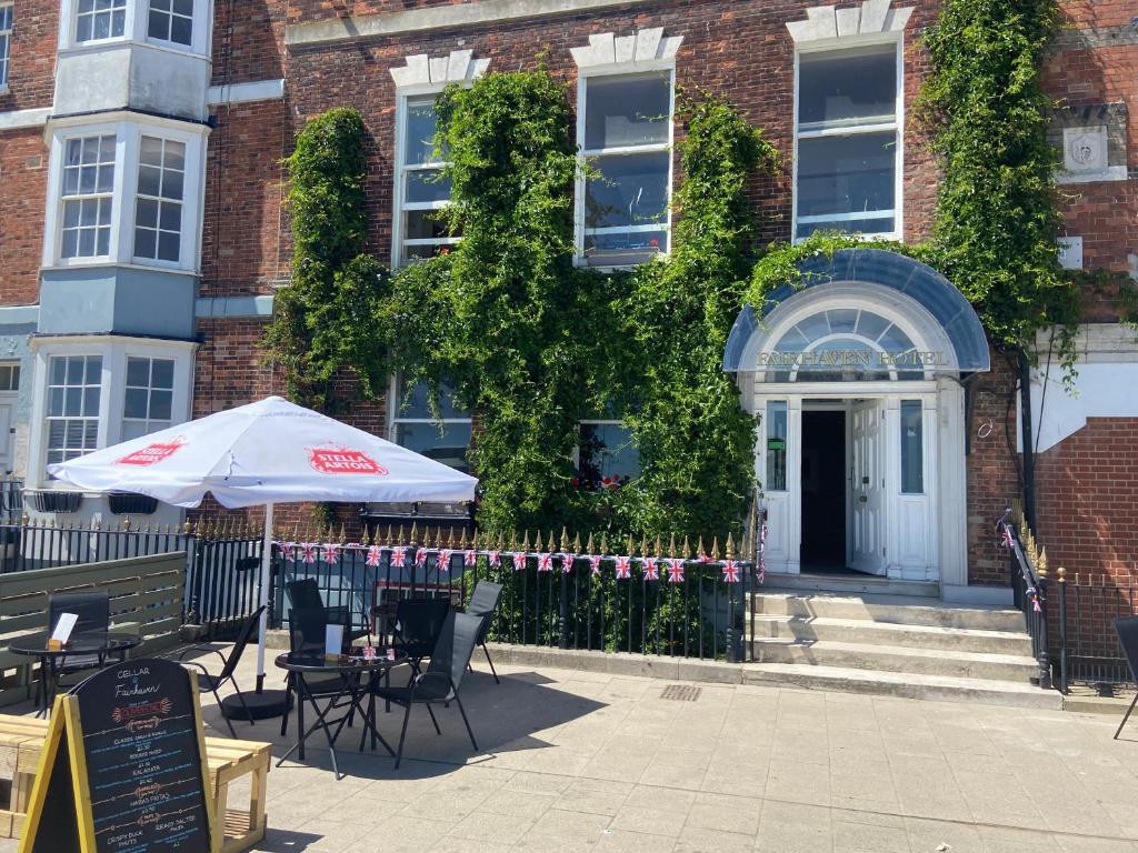 a building with chairs and an umbrella in front of it at The Fairhaven Hotel in Weymouth