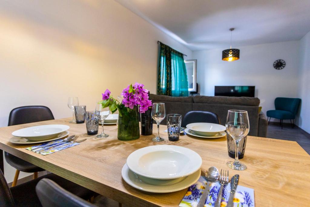 a wooden table with plates and flowers on it at City Apartment Nora, old town located in Makarska