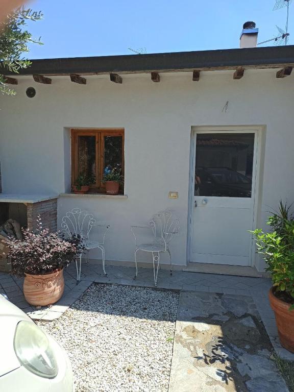 une maison blanche avec deux chaises et une porte dans l'établissement Casa La Gardenia, à Torre del Lago Puccini