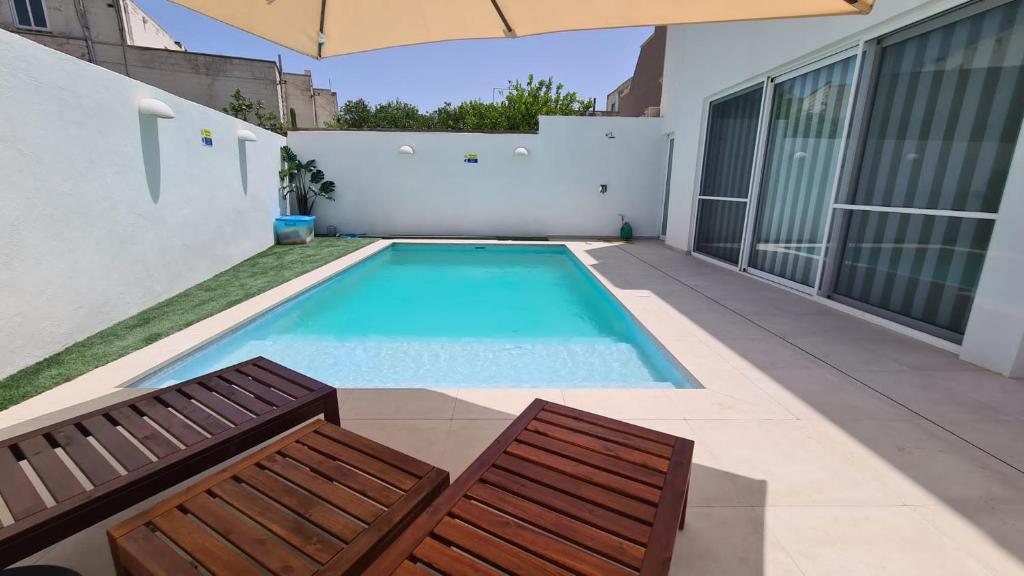 basen z 2 krzesłami i parasolem w obiekcie Modern and bright 3 bedroom villa with pool. w mieście San Ġwann
