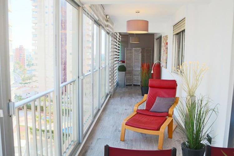 Cette chambre dispose d'une chaise rouge et de quelques fenêtres. dans l'établissement Appartement Rosa N&B met Groot Terras met Zeezicht -70m van Strand, à Calp