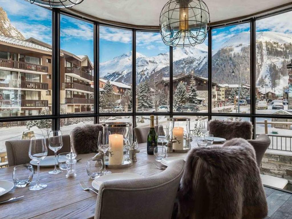 d'une salle à manger avec une table et une vue sur les montagnes. dans l'établissement Duplex luxueux 10p avec cheminée, 500m des pistes à Val d'Isère - FR-1-567-11, à Val dʼIsère