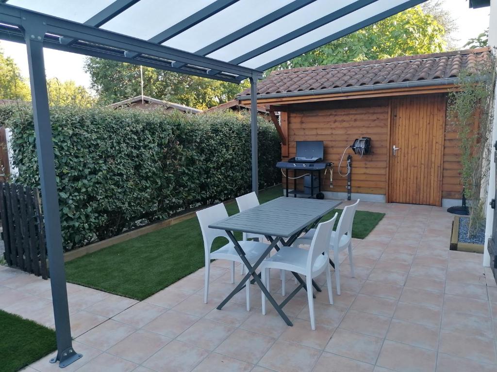 a patio with a table and chairs under a pergola at Maison cosy Bassin d'arcachon in Arès