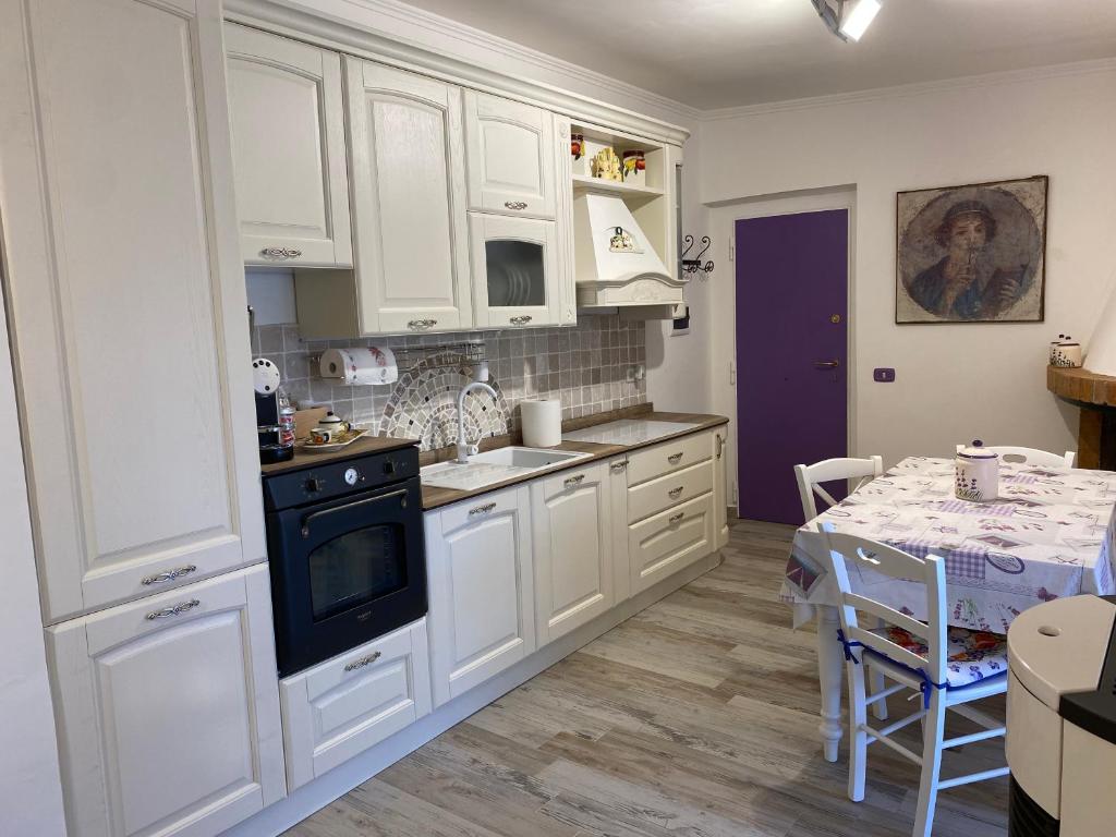 una cocina con armarios blancos y una mesa. en Casa San Benedetto, en Vicovaro
