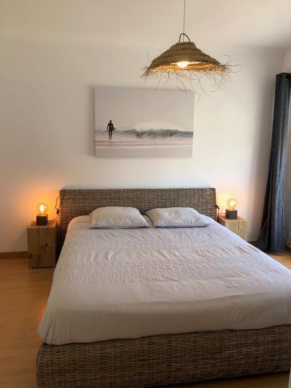 une chambre avec un lit et un tableau au mur dans l'établissement DEMOISELLES - Appartement 1 chambre, à Saint-Jean-de-Monts