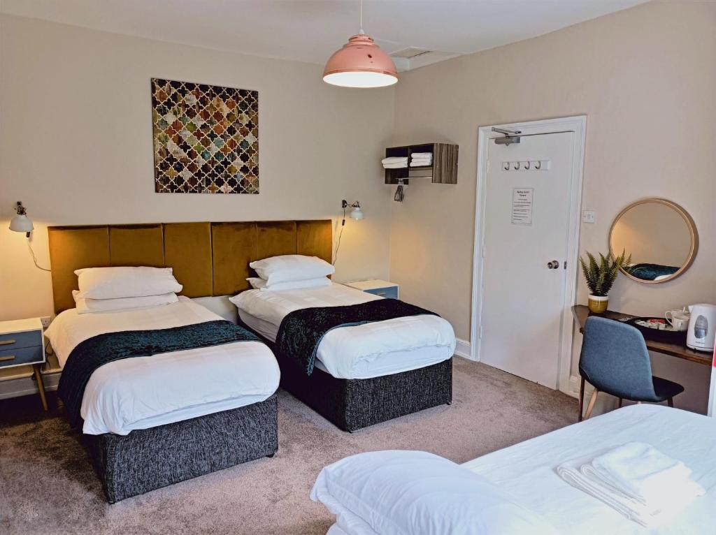 Habitación de hotel con 2 camas y escritorio en Spring Grove B&B, en Huddersfield