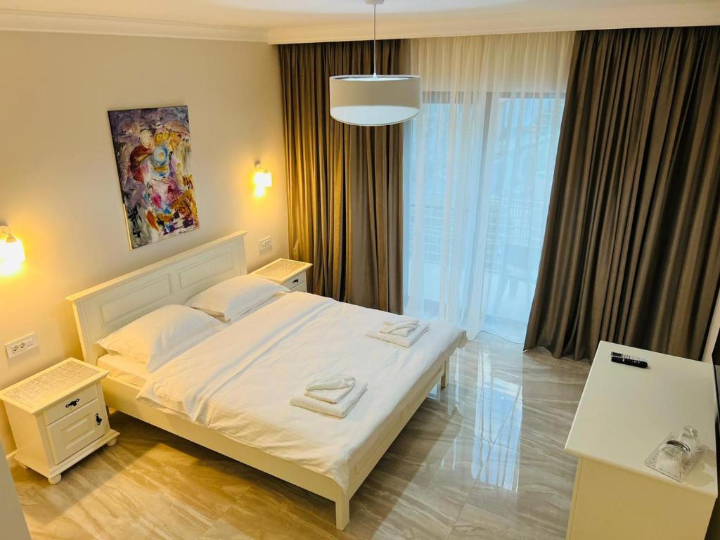 una camera da letto con un letto bianco e una grande finestra di M House Băile Herculane a Băile Herculane