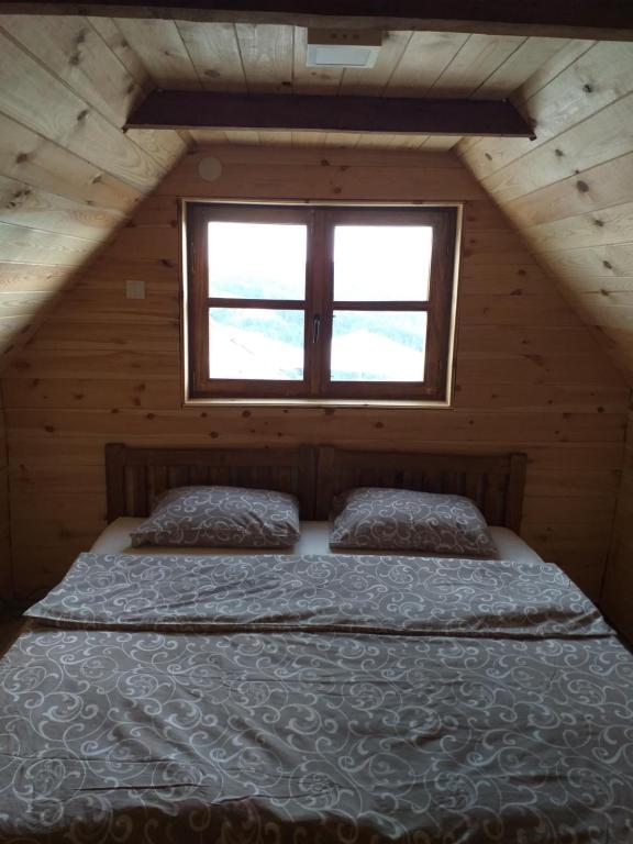 uma cama num chalé de madeira com uma janela em Koliba Kod Begija em Paljevine