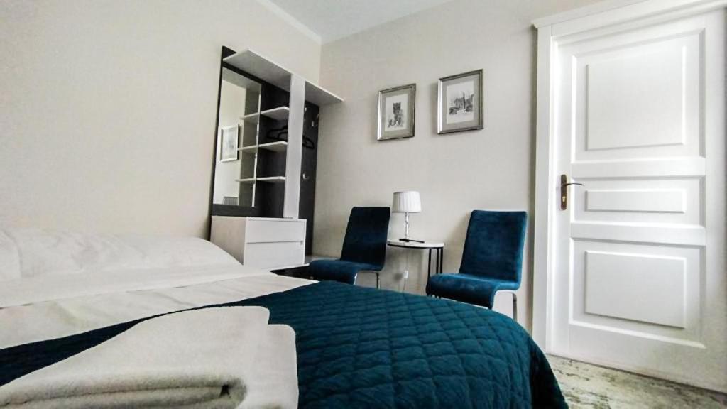 a bedroom with a bed and two blue chairs at Apartamenty i pokoje gościnne KOŁODZIEJÓWKA in Sandomierz