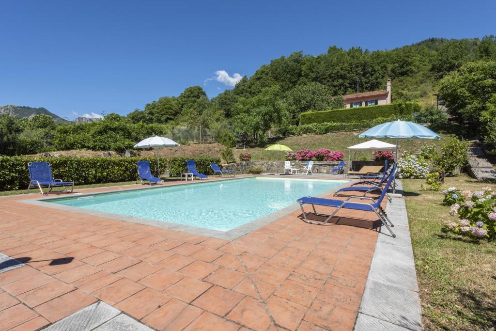 una piscina con sillas y sombrillas en un patio en Villa Popiglio, en San Marcello Pistoiese