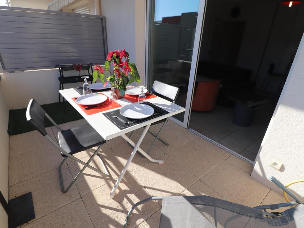 une table et des chaises avec un vase de fleurs. dans l'établissement Appartement T2 avec Terrasse, Parking et Piscine à Sète, proche Plage - FR-1-472-117, à Sète