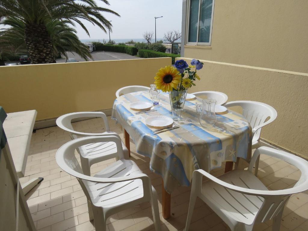 une table avec des chaises et un vase de fleurs dessus dans l'établissement Charmant T2 de 40m² en front de mer avec loggia, terrasse et parking privé - Sète - FR-1-472-127, à Sète