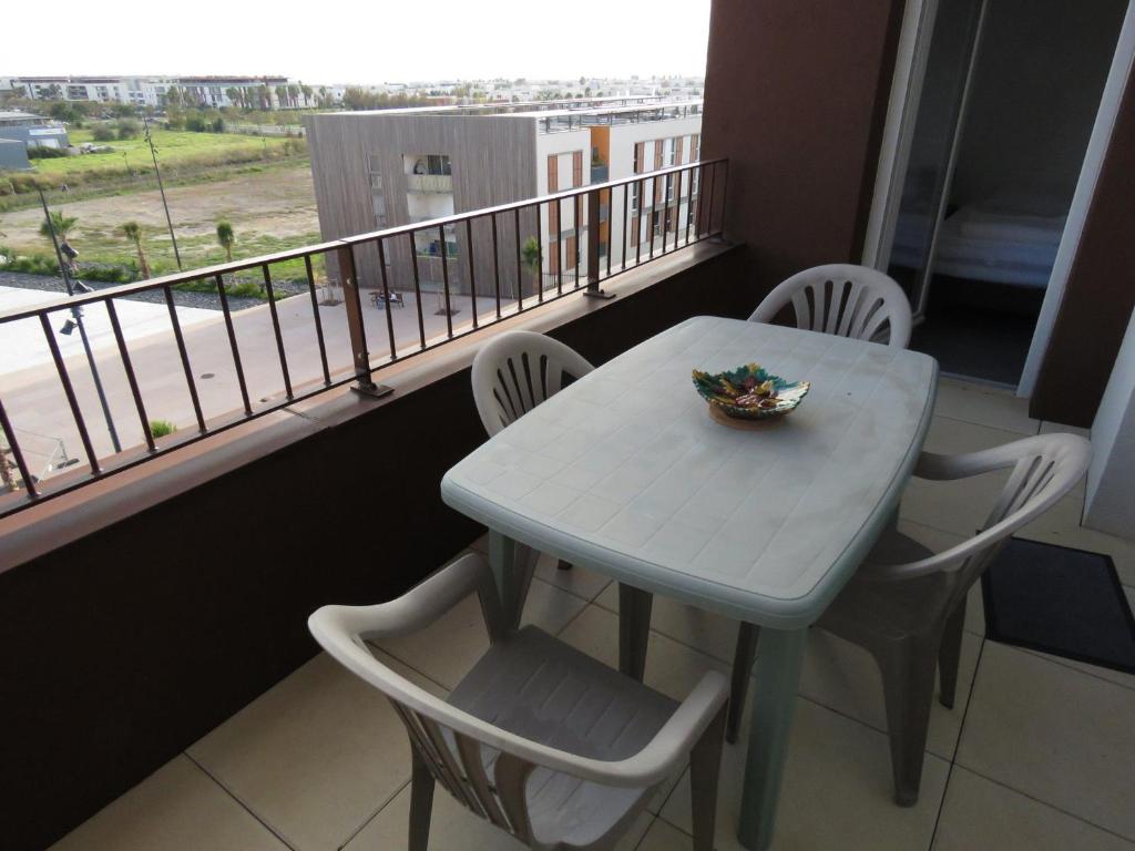 une table et des chaises blanches sur un balcon avec une table et un bol dans l'établissement T2 43m² dernier étage avec terrasse et parking à Sète - FR-1-472-148, à Sète