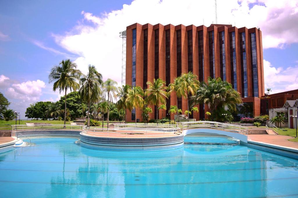 a large swimming pool in front of a tall building at Tibisay Hotel Maturin in Maturín