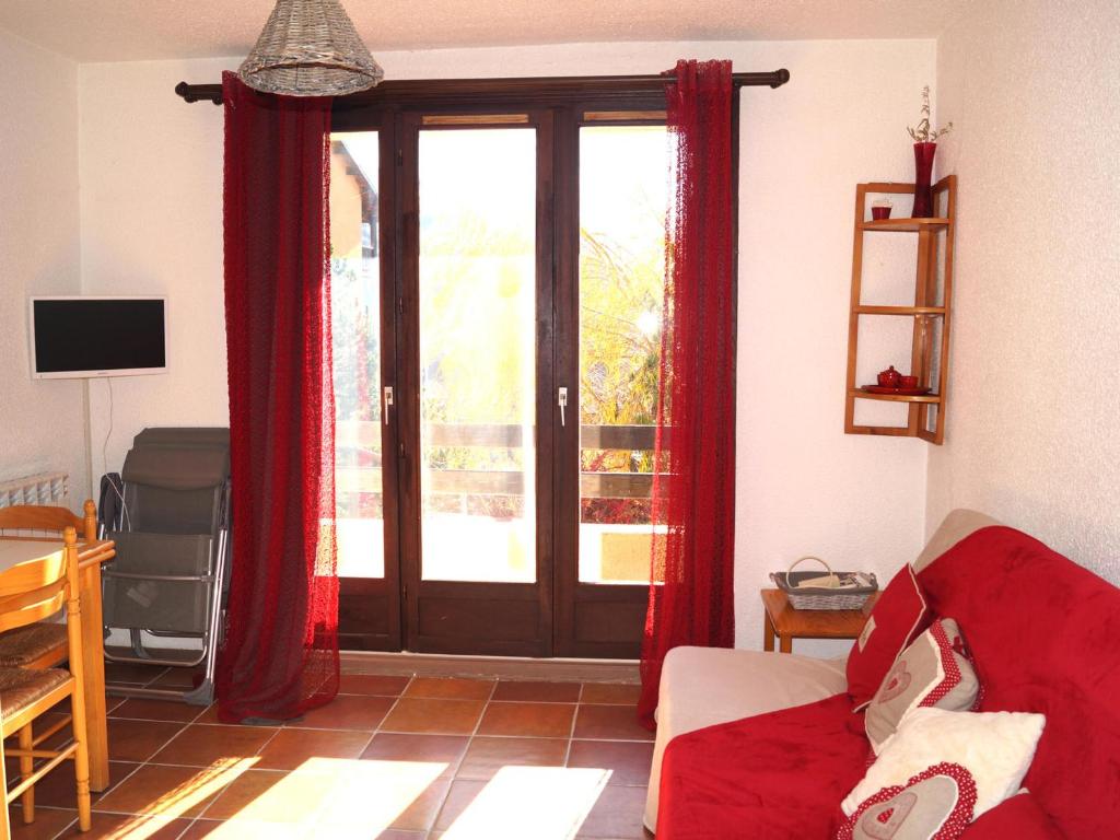 - un salon avec des rideaux rouges et une porte coulissante en verre dans l'établissement Charmant appartement T2 à Barcelonnette, 4 pers, balcon avec vue, parking - FR-1-165A-104, à Barcelonnette