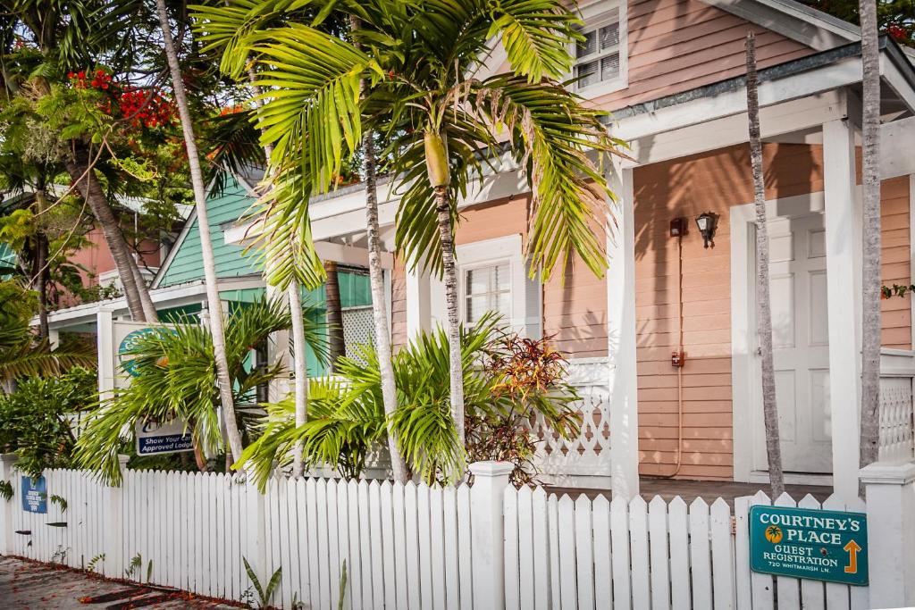 a white fence in front of a house with a palm tree at Courtney's Place Historic Cottages & Inns in Key West