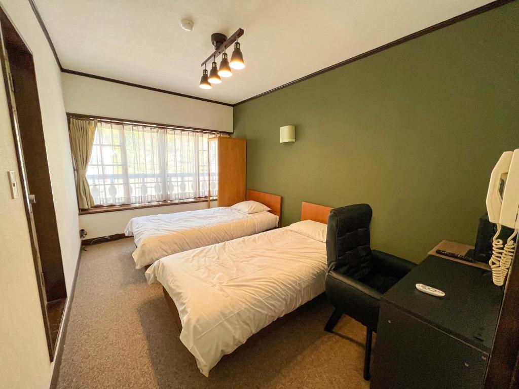 a bedroom with two beds and a desk and a chair at Norikura Kogen - irodori - - Vacation STAY 91520v in Matsumoto