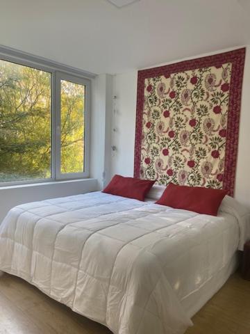 een slaapkamer met een groot wit bed en 2 ramen bij Rubí, cálido y centrico in Ushuaia