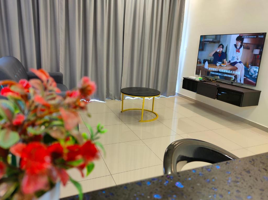 - un salon avec une télévision, une table et des fleurs dans l'établissement New Cozy Mvista Homestay at Bayan Lepas Factory Area, à Bayan Lepas
