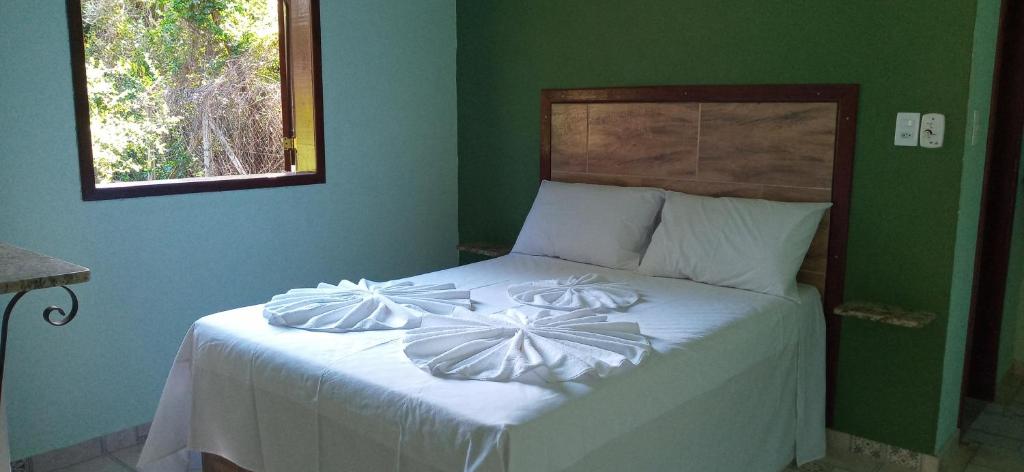 a bedroom with a bed with white sheets and a green wall at Chalés Jardim da Serra in Serra do Cipo