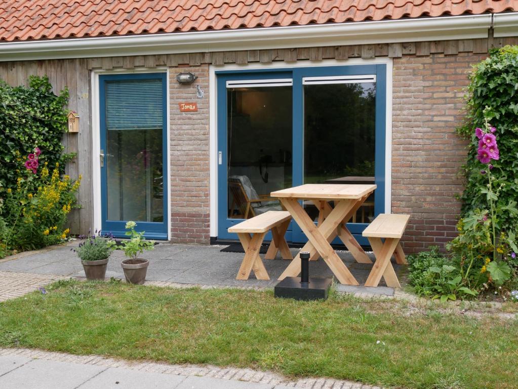 a wooden picnic table in front of a building at Jonas - Luxe appartement naast de duinen in Oosterend
