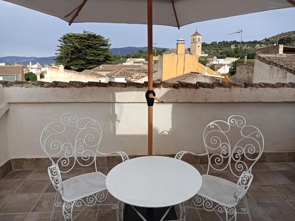 ein Tisch und zwei Stühle und ein Sonnenschirm auf dem Balkon in der Unterkunft CASA BEATLES DEL VALLE in Pinos del Valle