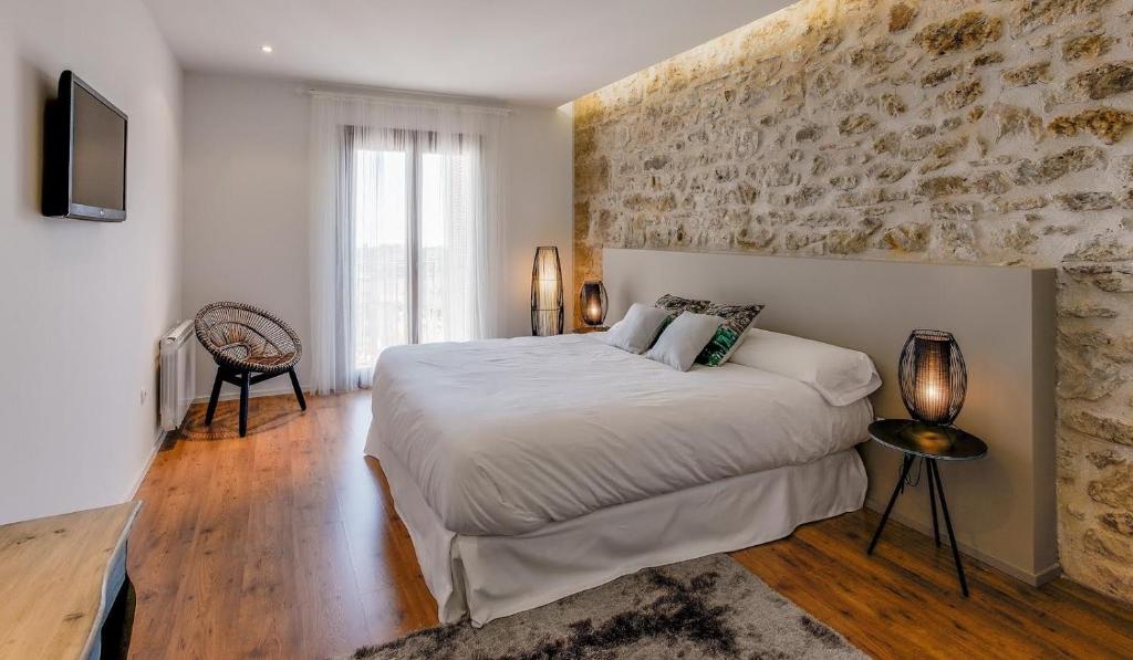 Hotel Boutique Abadia del Maestrat في Sarratella: غرفة نوم بسرير كبير وجدار حجري