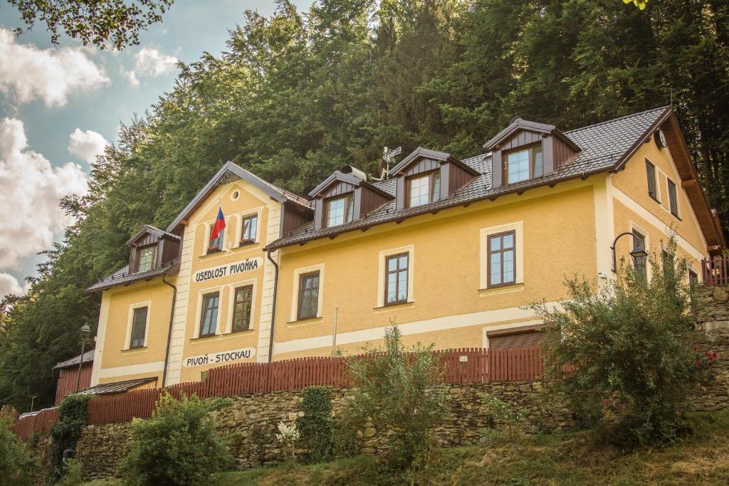 a large yellow building on a hill with trees at Usedlost Pivoňka in Mnichov