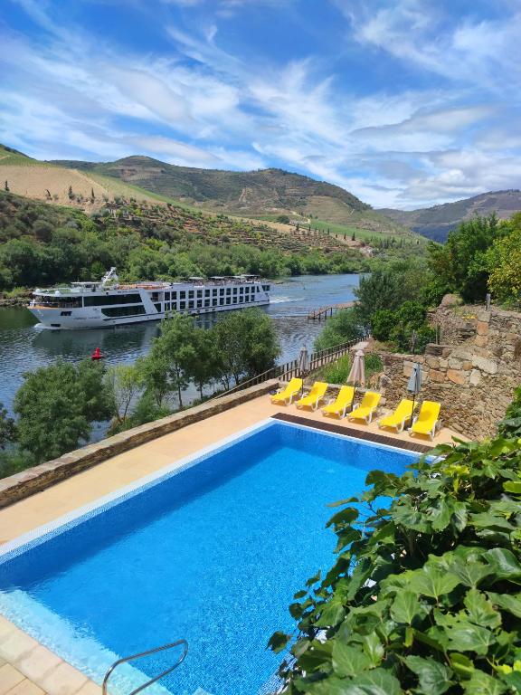 a swimming pool next to a river with a cruise ship at Hotel Casa do Tua in Foz Tua