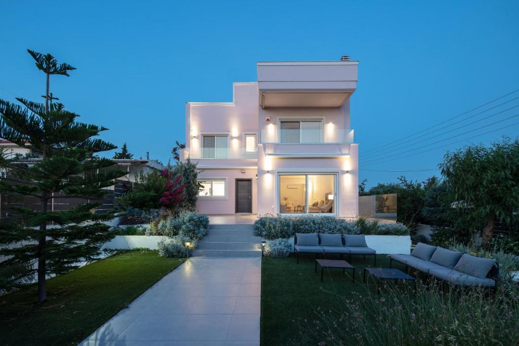 Casa blanca con jardín por la noche en Grand Panoramic Villa Lagonissi, en Lagonisi