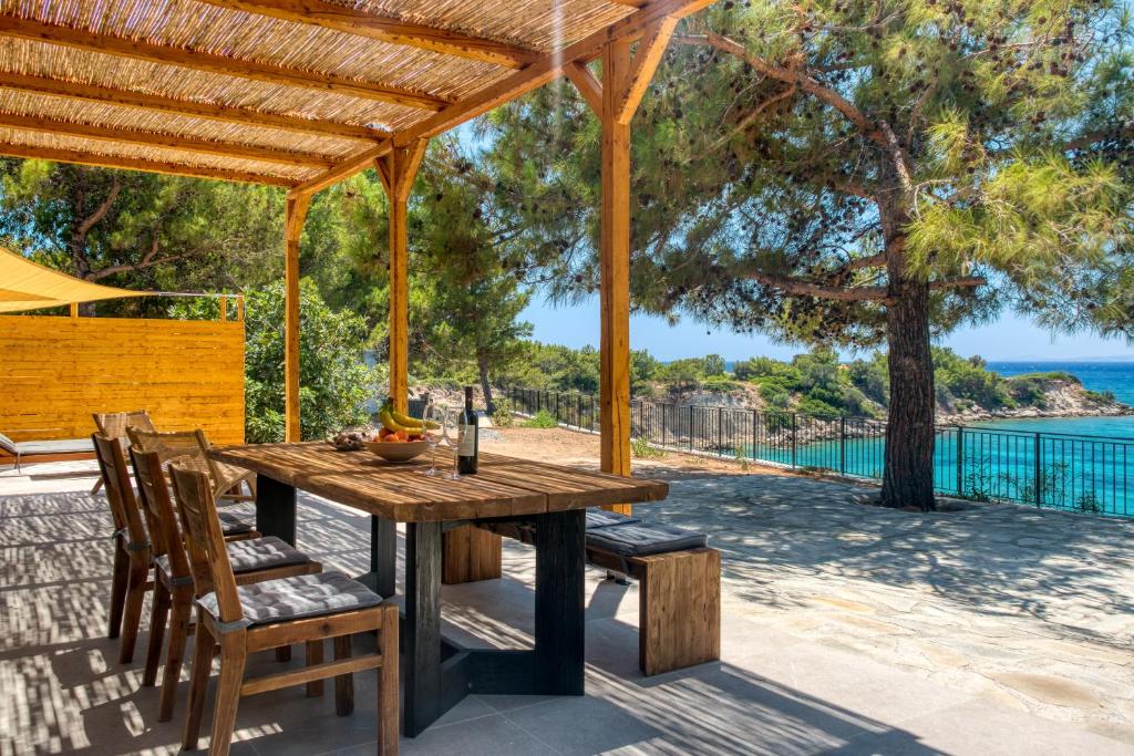 a wooden table and chairs under a wooden pergola at Kavos beach house in Pefki