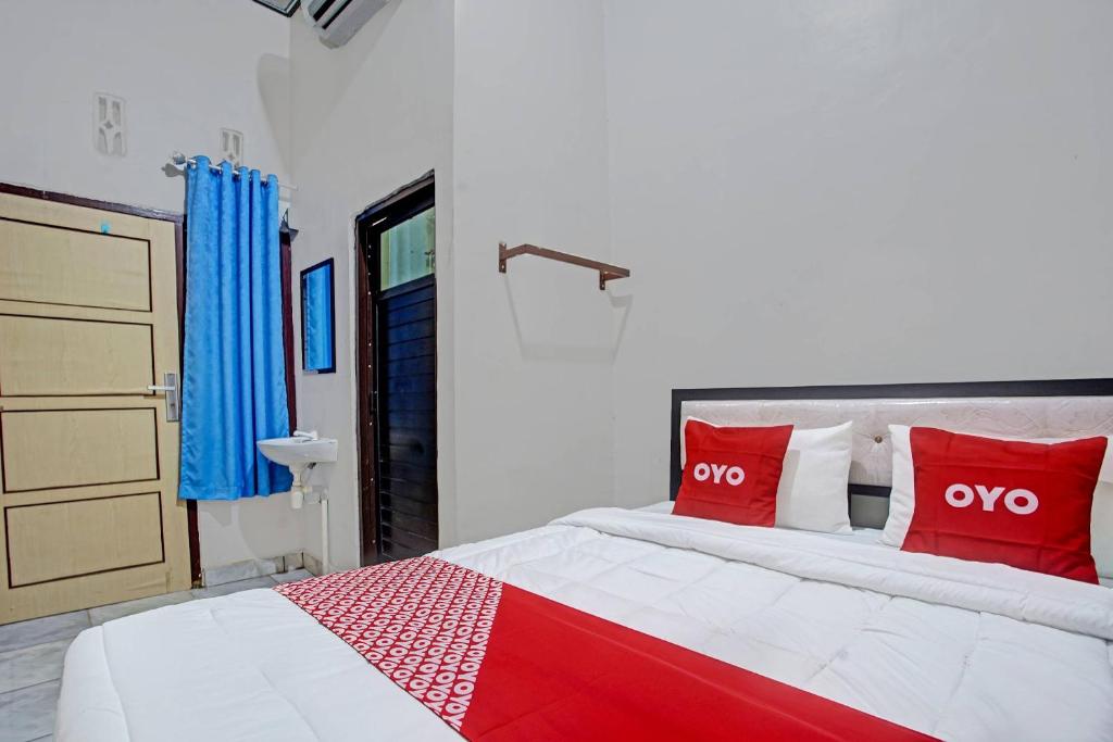 1 dormitorio con 1 cama grande con almohadas rojas en OYO 3439 Wisma Tri Handayani Syariah en Bandar Lampung