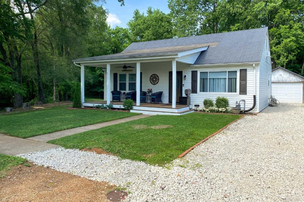 ein weißes Haus mit einer Veranda und einer Auffahrt in der Unterkunft Quaint Creekside Cottage with Porch and Backyard! in Lexington